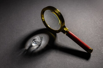 magnifying glass standing on dark surface with beam of light falling on diamond