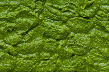 Homemade pesto-like dip made of arugula leaves, walnuts, parmesan, garlic, and olive oil. Background texture.