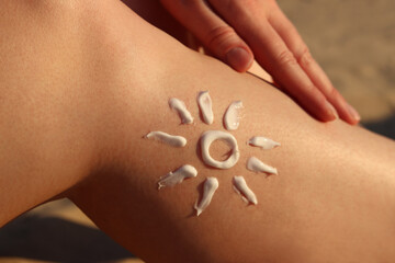 SPF sun protection skin from sunburn on the beach. Drawing of the sun on a woman's leg made with sunscreen. Relaxation on the beach. Cream for safe tanning on the beach in summer. Relaxation concept