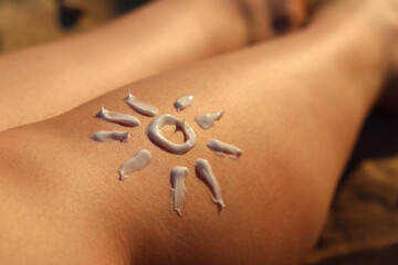 SPF sun protection skin from sunburn on the beach. Drawing of the sun on a woman's leg made with sunscreen. Relaxation on the beach. Cream for safe tanning on the beach in summer. Relaxation concept