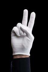 Gesturing of the symbol of peace and victory with two fingers of a hand in white gloves on a black background