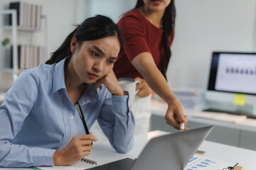Stressed asian businesswomen working with laptop in office, teamwork and problem solving