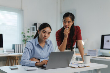 Focused asian businesswomen working on laptop in modern office
