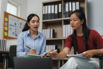 Businesswomen working together using laptop and taking notes in office meeting