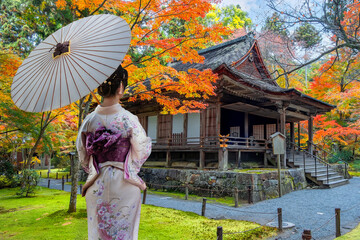 Japanese Woman in Traditional Kimono Dress at Sanzen-in temple  with a colorful autumn garden in...
