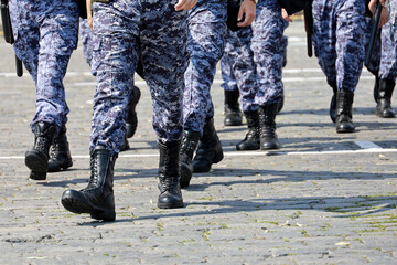 Legs of soldiers of military forces in camouflage, men walking down the city street