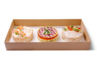 An elegant catering box featuring three beautifully styled layered salads shaped like cakes