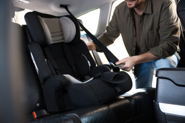 Happy man with child safety seat inside car, closeup
