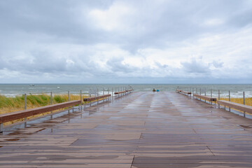 Wooden bridge walk and stair to the sand beach with marram grass (beach grass) under blue sky in summer, Dutch north sea coastline in Egmond aan Zee, Municipality of Bergen, Noord Holland, Netherlands