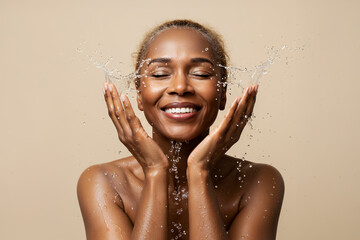 Portrait of senior African woman washing face with water splash on beige background, copy space