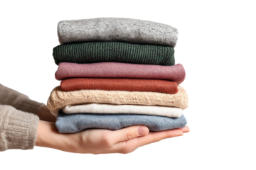 Hands holding stack of folded colorful clothes isolated on transparent background.