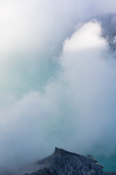 View of a dramatic landscape where the earth meets the sky in a hazy embrace of blue and grey, Ijen Volcano Crater, East Java, Indonesia.