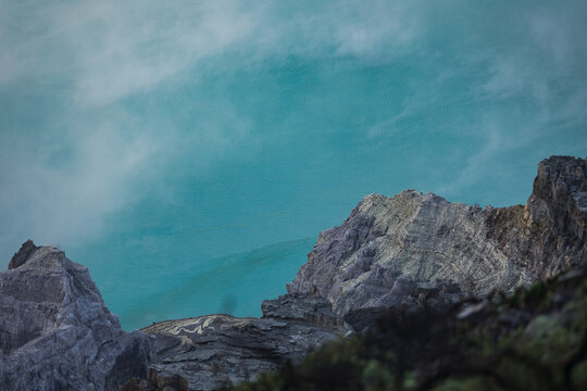 View of jagged grey rocks cutting through a milky, ethereal turquoise sky, the scene exuding a surreal and otherworldly atmosphere, Ijen Volcano Crater, East Java, Indonesia.