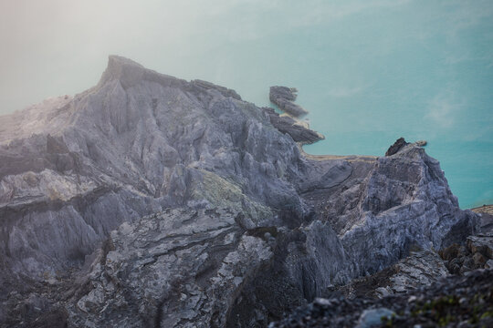 View of jagged, gray volcanic rocks rise against the surreal turquoise sky, a stark contrast of textures and colors that captivates the eye, Ijen Volcano Crater, East Java, Indonesia.