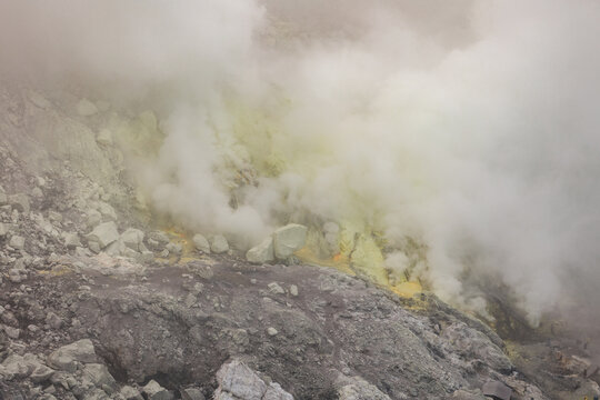 View of ethereal sulfuric plumes rising from the volcanic landscape, a scene of geothermal activity and rocky textures, Ijen Volcano Crater, East Java, Indonesia.