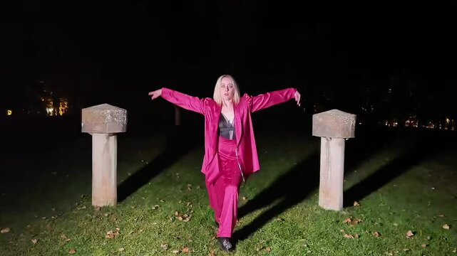 Young woman dancing waacking in a park at night
