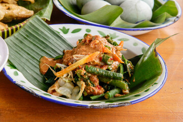 Indonesian vegetable salad with peanut sauce or pecel on vintage enamel plate  lined with banana leaves
