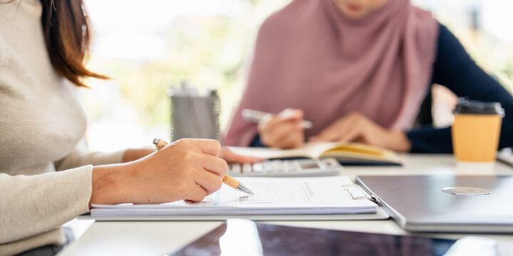 Business meeting with diverse professionals. Two women discussing work, taking notes. Professional attire, diverse team, collaborative environment. Diverse people business corporate meeting.
