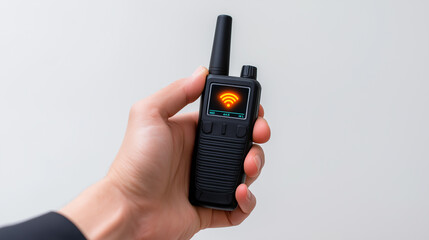 Fototapeta premium Hand holding a walkie-talkie with a glowing red signal icon on a plain background. 