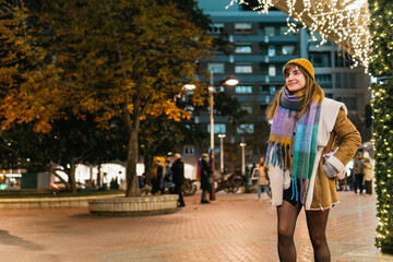 Young woman enjoying christmas lights in city at night