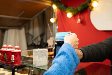 Woman paying with contactless credit card at christmas market stall