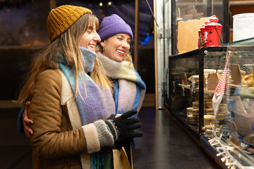 Two smiling women choosing sweets at christmas market