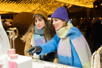 Two friends choosing gifts at christmas market