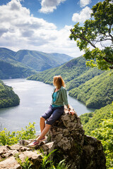 Naklejka premium woman overlooking Tarnita lake bright green summer landscape
