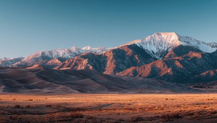 Naklejka premium Sunrise over snow-capped mountains and dunes