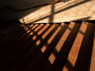 Shadows dancing on stone steps in a well-lit interior staircase during the afternoon light
