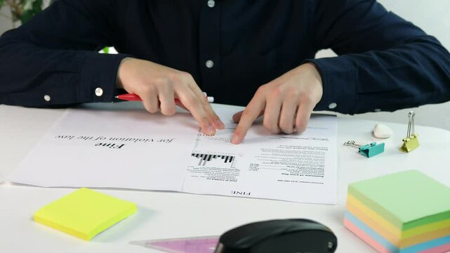 A businessman studies a fine received for violations in doing business and makes notes on it. Shadow business, the illegal side of business and punishment.
