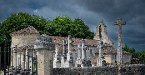 A cemetery filled with ornate stone crosses stands adjacent to a historic church in...