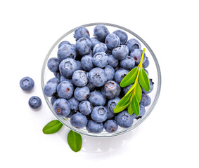 Fresh organic berry blueberries with green leaves in a round glass bowl close-up. Fruity still life...