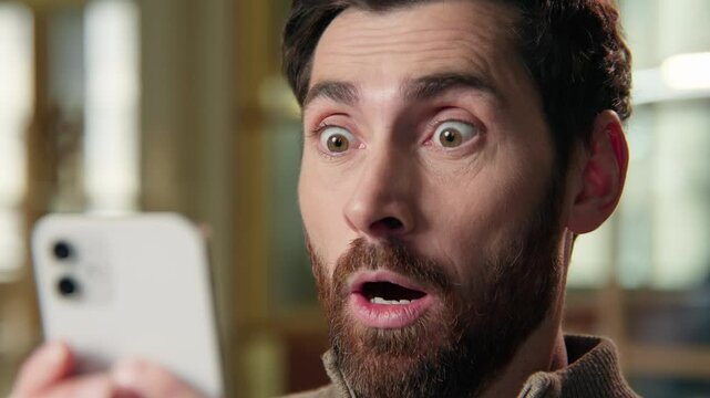 Shocked business man close up scared big eyes guy looking at mobile phone amazing shock news businessman at office frightened Caucasian male afraid stunned astonishment emotion unbelievable excitement