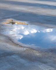 Reflection of clouds in a puddle on pavement
