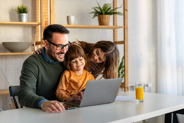 Happy family with kids having fun using laptop together, parent and children relaxing at home