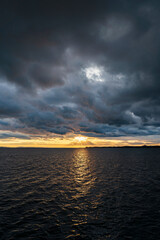sunset over Lake Constance Bodensee with dark clouds and a small stripe of golden backlight seen...