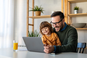Happy single parent with cute excited small kid son using laptop computer at home. Technology