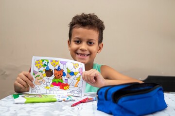 Young boy with colorful drawing and art supplies.