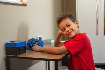 Smiling boy at desk with school supplies.