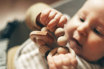 Close-up of a baby gnawing on a wooden teething toy, showcasing their curiosity and oral exploration. The image captures the baby's focus and engaging hand movements.