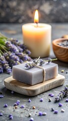 A luxurious lavender soap bar sits on a wooden dish, next to a lit candle and a bowl of dried lavender, creating a serene spalike atmosphere