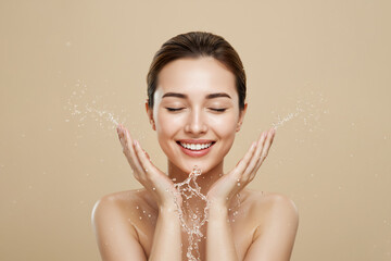Young woman washing face with water splash on beige background, copy space