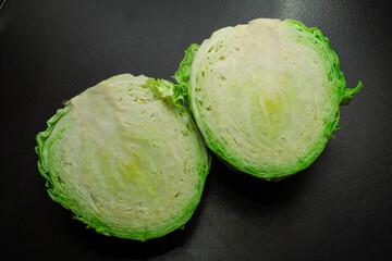 Fresh green cabbage with a half on a black background.
Fresh ripe cabbage. Vegetarianism. The...