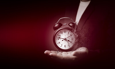 Businessman's hand shows a black alarm clock dissolving. Concept of effective time management and...