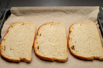 Close-up of tomato bruschetta on artisan bread slices with fresh sliced ​​tomatoes, parmesan cheese and herbs on a baking sheet in the oven while cooking. Food preparation process, bruschetta, sandwic
