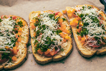 Close-up of tomato bruschetta on artisan bread slices with fresh sliced ​​tomatoes, parmesan cheese and herbs on a baking sheet in the oven while cooking. Food preparation process, bruschetta, sandwic