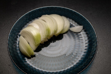 Thinly sliced ​​white onion on blue plate, onion sliced ​​for cooking.
Vegetarianism. Home...