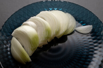 Thinly sliced ​​white onion on blue plate, onion sliced ​​for cooking.
Vegetarianism. Home...