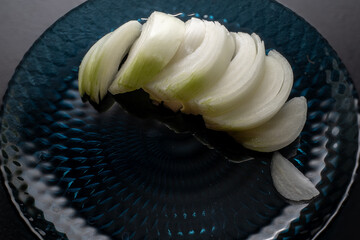 Thinly sliced ​​white onion on blue plate, onion sliced ​​for cooking.
Vegetarianism. Home...